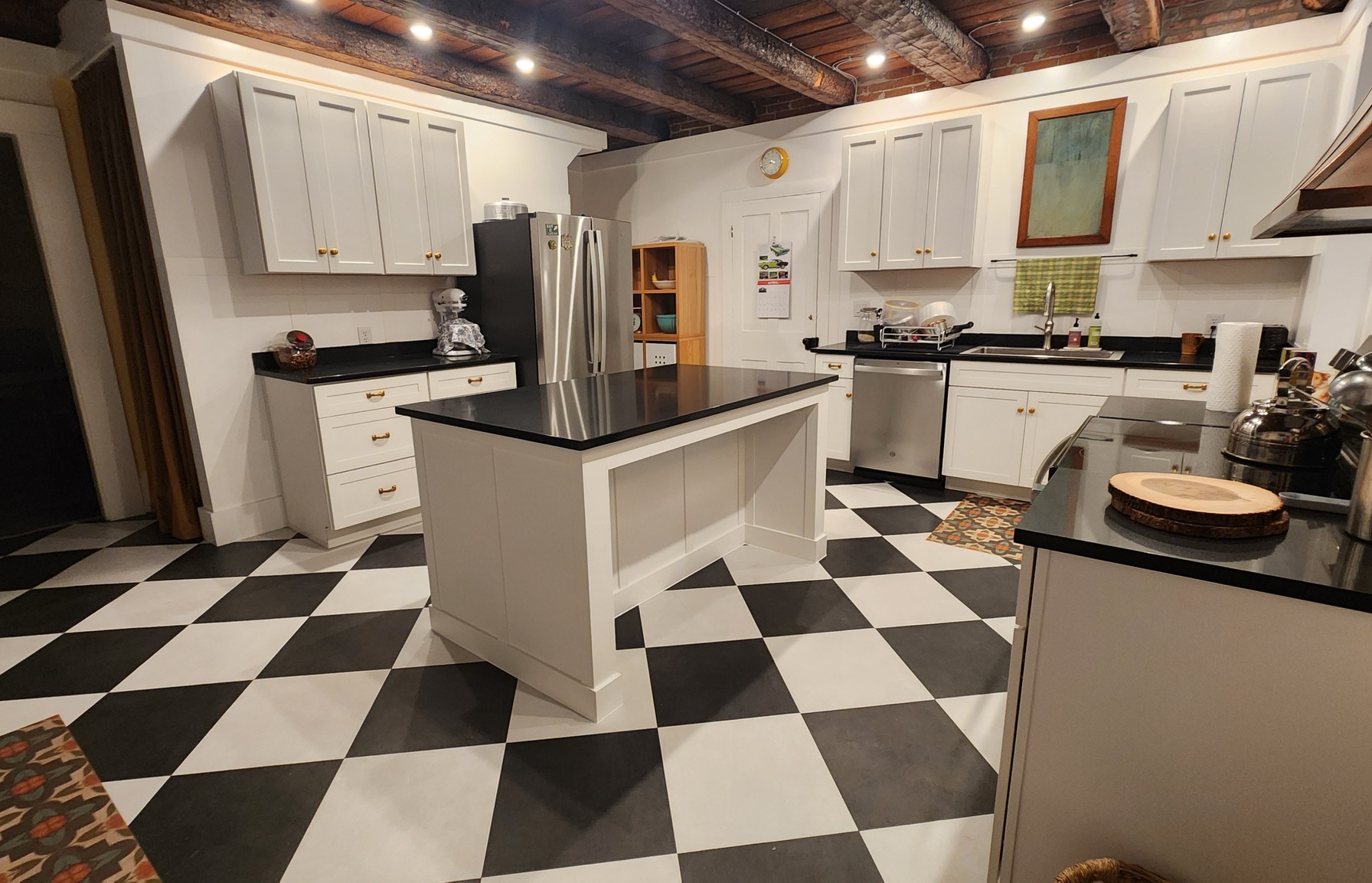 Kitchen with white cabinets, a central island and black-and-white checkerboard flooring